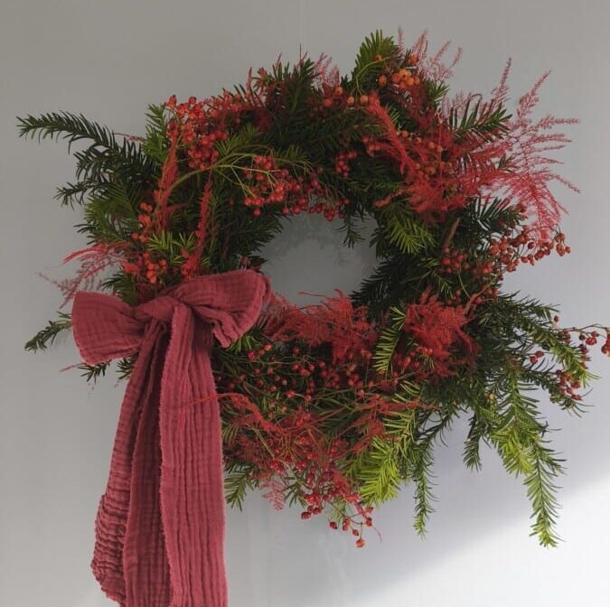 Handgemaakte kerstkrans uit Lede (Oost-Vlaanderen) met dennengroen, eucalyptus en bessen – bloemstyling van Katrien voor stijlvolle kerstdecoratie.